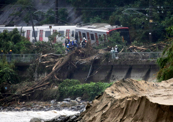 7일(현지시간) 일본 사가현 가라쓰시에 폭우로 인한 산사태로 열차가 탈선해 응급 구조대가 구조작업을 하고 있다. AFP 연합뉴스