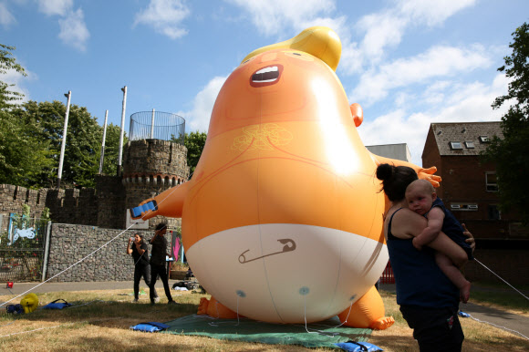 운동가들이 10일(현지시간) 런던 북쪽에서 도널드 트럼프 미국 대통령을 ‘오렌지 베이비’로 묘사한 거대한 풍선을 부풀려 세우고 미국 대통령의 방문과 동시에 시위를 벌이고 있다. AFP 연합뉴스