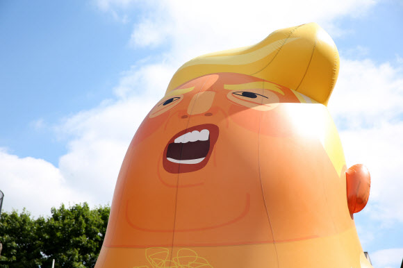 운동가들이 10일(현지시간) 런던 북쪽에서 도널드 트럼프 미국 대통령을 ‘오렌지 베이비’로 묘사한 거대한 풍선을 부풀려 세우고 미국 대통령의 방문과 동시에 시위를 벌이고 있다. AFP 연합뉴스