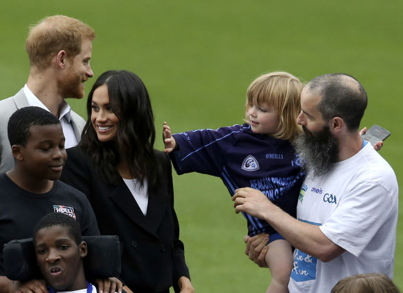 영국 서식스 공작 해리 왕자(왼쪽 뒤)와 서식스 공작부인 메건(오른쪽 세 번째)이 11일(현지시간) 아일랜드 더블린을 방문한 두 번째 날 크로크 파크 (Croke Park)에서 어린 아이가 서식스 공작부인 메건의 머리카락을 만지고 있다. AP 연합뉴스