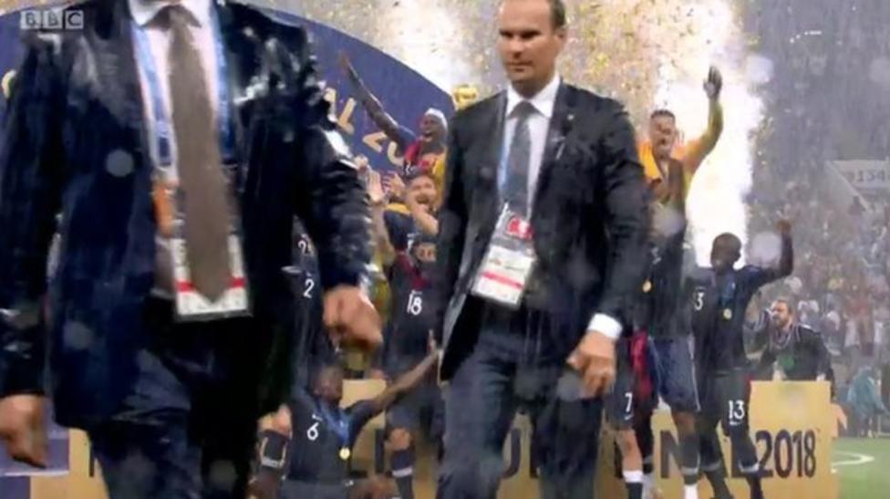 프랑스 축구대표팀의 주장 위고 요리스가 20년 만에 차지한 두 번째 국제축구연맹(FIFA) 월드컵 트로피를 들어올리는 순간 양복을 입은 남자들이 중계 카메라의 시야를 가리며 지나가고 있다.