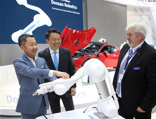 지난달 독일 뮌헨에서 열린 ‘오토매티카 2018’에서 박정원(왼쪽) 두산그룹 회장이 독일 로봇시장 한 딜러업체 대표와 이야기를 나누고 있다. 두산 제공