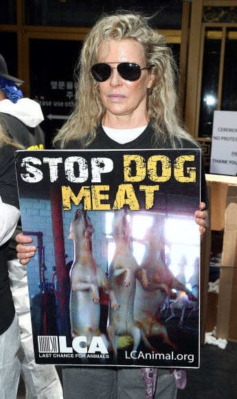 미국 영화배우 킴 베이신저가 초복인 지난 17일(현지시간) 캘리포니아주 로스앤젤레스(LA) 도심에 위치한 한국 총영사관 앞에서 ‘개고기 식용 금지’라고 적힌 피켓을 든 채 시위하고 있다.  로스앤젤레스 AFP 연합뉴스