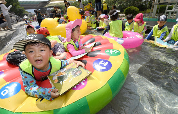 24일 서울 송파구 성내천 물놀이장에서 어린이들이 ‘여름행복문고’에서 빌린 책을 읽으면서 물놀이를 즐기고 있다. 2018.7.24 박지환 기자 popocar@seoul.co.kr