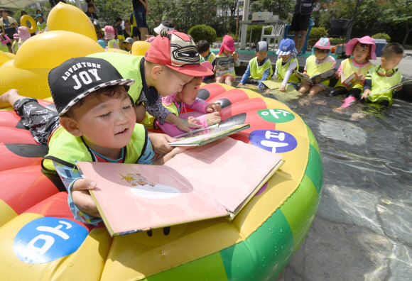 24일 서울 송파구 성내천 물놀이장에서 어린이들이 ‘여름행복문고’에서 빌린 책을 읽으면서 물놀이를 즐기고 있다. 2018.7.24 박지환 기자 popocar@seoul.co.kr