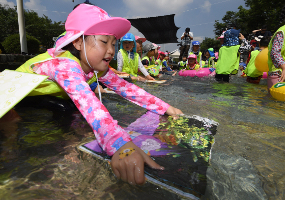 24일 서울 송파구 성내천 물놀이장에서 어린이들이 ‘여름행복문고’에서 빌린 책을 읽으면서 물놀이를 즐기고 있다. 2018.7.24 박지환 기자 popocar@seoul.co.kr