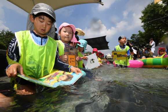 24일 서울 송파구 성내천 물놀이장에서 어린이들이 ‘여름행복문고’에서 빌린 책을 읽으면서 물놀이를 즐기고 있다. 2018.7.24 박지환 기자 popocar@seoul.co.kr