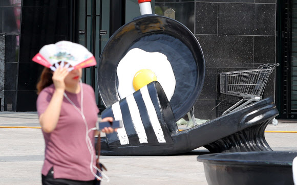 26일 오전 현대백화점 대구점 앞에 더위에 익은 달걀프라이와 녹아내린 슬리퍼 조형물이 시민들의 눈길을 사로잡고 있다. 이날 대구 중구청에 따르면 최근 보행을 방해하고 더위를 더욱 부채질하는 듯한 느낌이 들어 철거를 원한다는 내용의 민원이 들어와 관련 규정을 검토한 뒤 백화점 측에 철거를 요청했다. 2018.7.26  연합뉴스