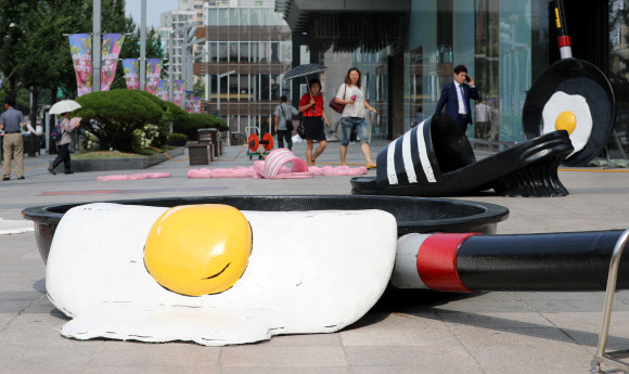 26일 오전 현대백화점 대구점 앞에 더위에 익은 달걀프라이와 녹아내린 슬리퍼 조형물이 시민들의 눈길을 사로잡고 있다. 이날 대구 중구청에 따르면 최근 보행을 방해하고 더위를 더욱 부채질하는 듯한 느낌이 들어 철거를 원한다는 내용의 민원이 들어와 관련 규정을 검토한 뒤 백화점 측에 철거를 요청했다. 2018.7.26  연합뉴스