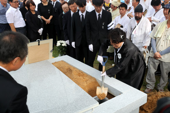 27일 오후 경기도 남양주시 모란공원에서 고(故) 노회찬 정의당 의원의 부인 김지선 씨가 고인의 유해를 안장한 뒤 취토하고 있다. 2018.7.27  연합뉴스