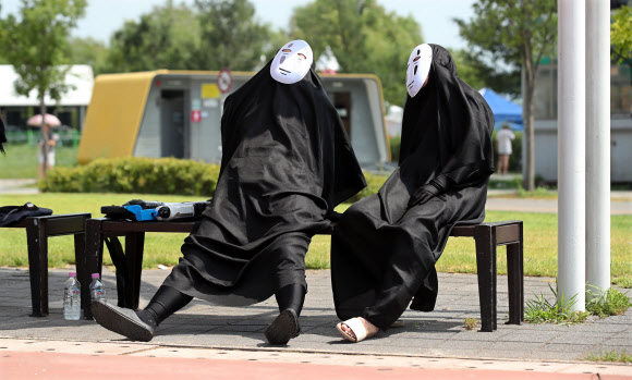 주말에도 푹푹 찌는 무더위가 계속되고 있는 4일 오후 서울 마포구 난지한강공원에서 한강 물싸움 축제 참가자가 일본 애니메이션 캐릭터 가오나시 분장을 하고 그늘에 앉아 휴식을 취하고 있다. 2018.8.4  연합뉴스