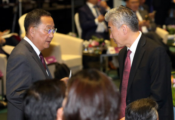 성 김 필리핀주재 미국대사(오른쪽)가 4일 싱가포르 엑스포 컨벤션센터에서 열린 아세안지역안보포럼(ARF) 포토세션이 끝난 뒤 리용호 북한 외무상에게 다가가 서류봉투를 전달한 뒤 이야기를 나누고 있다. 2018.8.4  연합뉴스