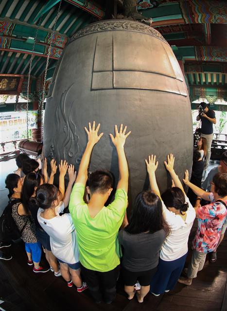 대학수학능력시험을 100일 앞둔 7일 서울 종로구 보신각에서 열린 ‘제7회 대학 합격기원 타종’ 행사에 참가한 수험생 및 학부모들이 보신각 종을 타종한 뒤 손을 대고 소원을 빌고 있다. 2018.8.7 뉴스1