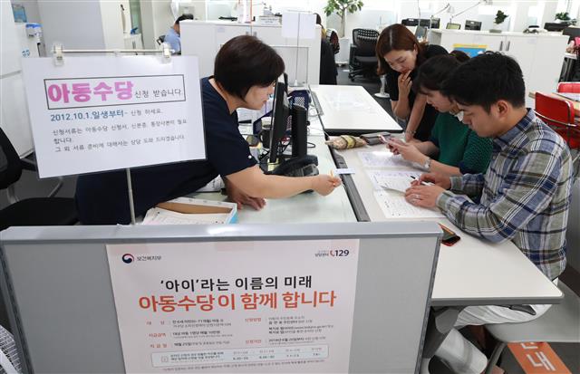 서울의 한 주민센터에서 한 부부가 다음달부터 아동 1명당 월 10만원씩 지급하는 아동수당을 신청하고 있다.  연합뉴스
