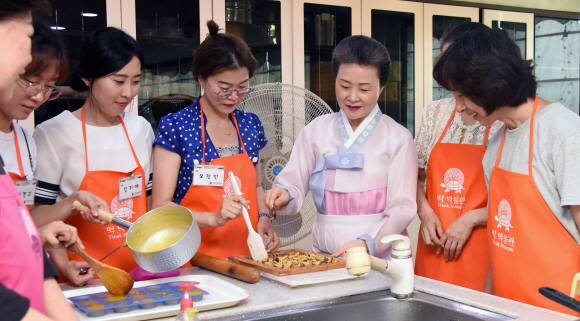 ‘한국의 다과상’을 수강하는 교사들이 윤숙자 한국전통음식연구소장으로부터 고구마강정의 요리 팁을 전달받고 있다.