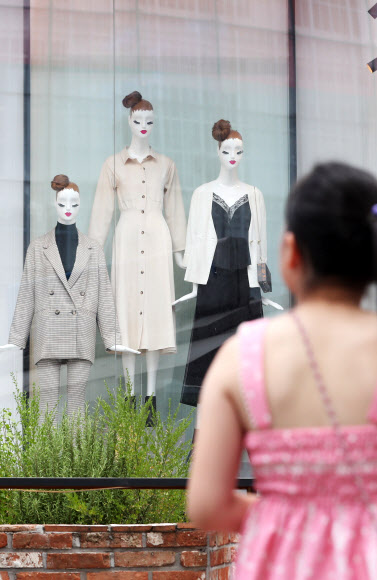 주말 기온이 36도까지 오른 12일 오후 서울 중구 명동 쇼핑가에서 여름옷을 입은 어린이가 가을 아이템을 착용한 마네킹이 설치된 쇼윈도를 바라보고 있다. 2018.8.12  연합뉴스