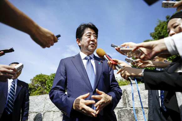 아베 신조 일본 총리가 12일 야마구치현 나가토시에 있는 부친 아베 신타로 전 외무상의 묘소를 참배한 뒤 기자들에게 둘러싸여 질문에 답하고 있다. 야마구치 교도 연합뉴스