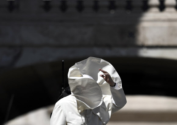 프란치스코 교황이 12일(현지시간) 바티칸 성 베드로 광장에서 이탈리아 청소년과의 미사 후 축복하는 가운데 바람이 불어 망토가 얼굴을 가리고 있다. AFP 연합뉴스