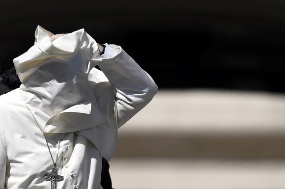 프란치스코 교황이 12일(현지시간) 바티칸 성 베드로 광장에서 이탈리아 청소년과의 미사 후 축복하는 가운데 바람이 불어 망토가 얼굴을 가리고 있다. AFP 연합뉴스