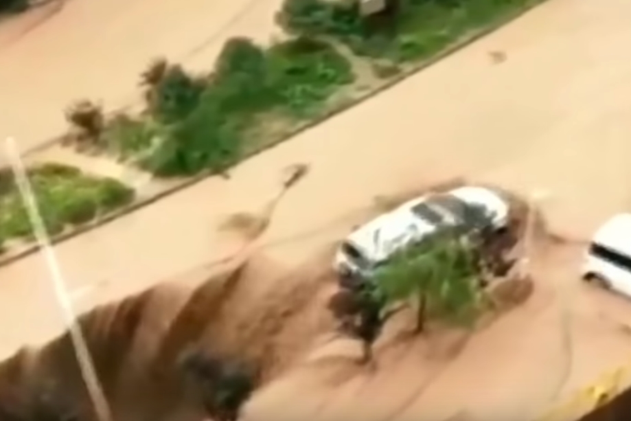 싱크홀에 뒷바퀴가 걸쳐져 추락 위기에 놓인 자동차