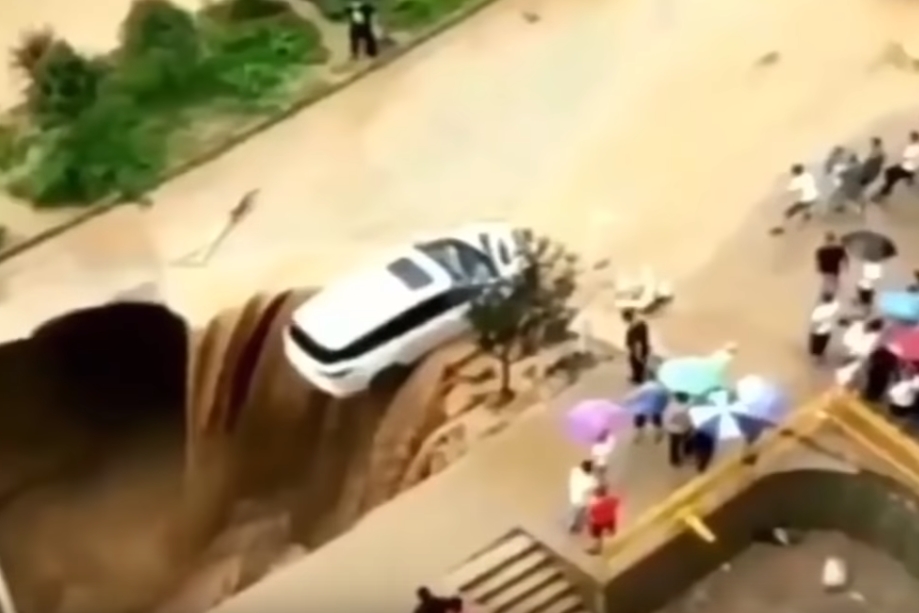 싱크홀에 뒷바퀴가 걸쳐져 추락 위기에 놓인 자동차