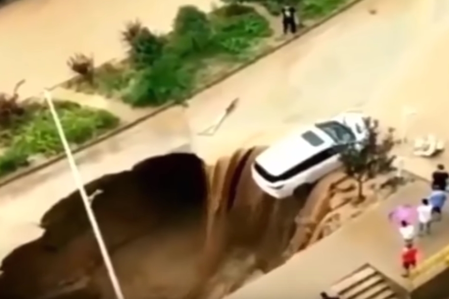 싱크홀에 뒷바퀴가 걸쳐져 추락 위기에 놓인 자동차