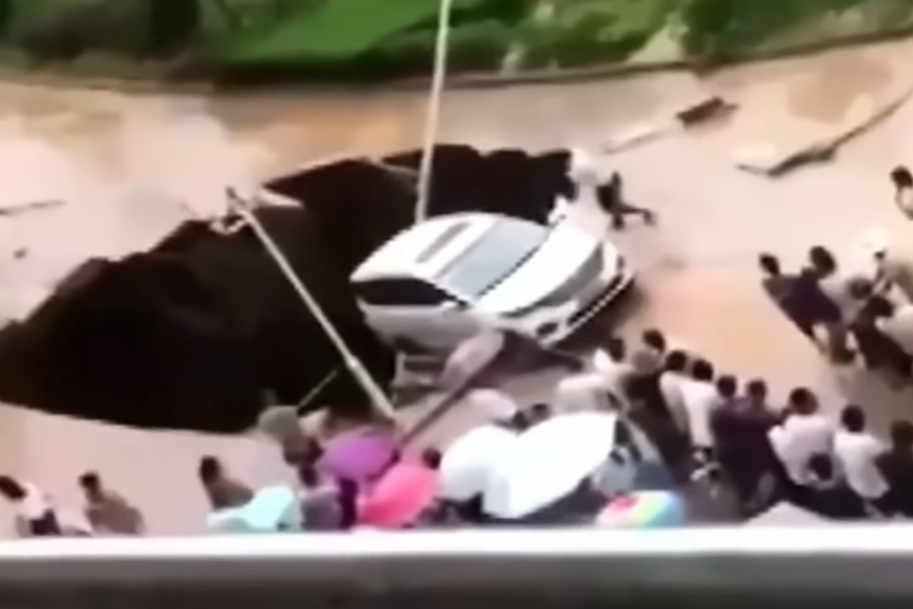 싱크홀에 뒷바퀴가 걸쳐져 추락 위기에 놓인 자동차