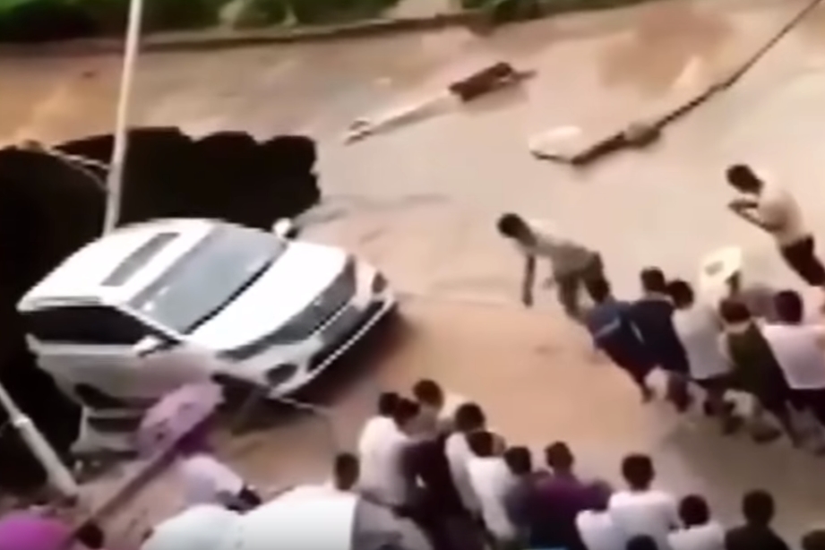 싱크홀에 뒷바퀴가 걸쳐져 추락 위기에 놓인 자동차