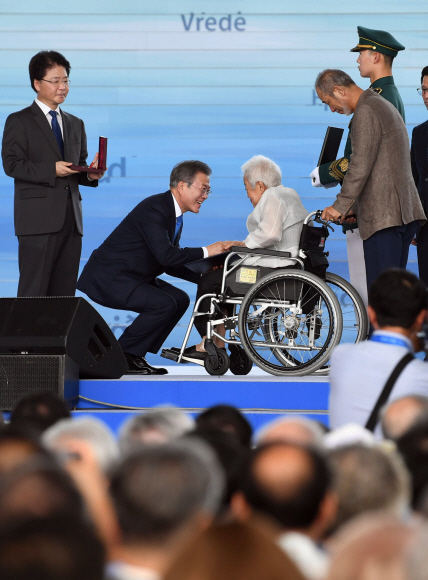 문재인 대통령이 15일 서울 용산구 국립중앙박물관 열린마당에서 열린 제73주년 광복절과 정부수립 70주년 경축식에서 독립유공자 故 손용우 씨 배우자 김경희 씨에게 건국훈장 애족장을 포상하고 있다.2018. 8. 15. 박윤슬 기자 seul@seoul.co.kr