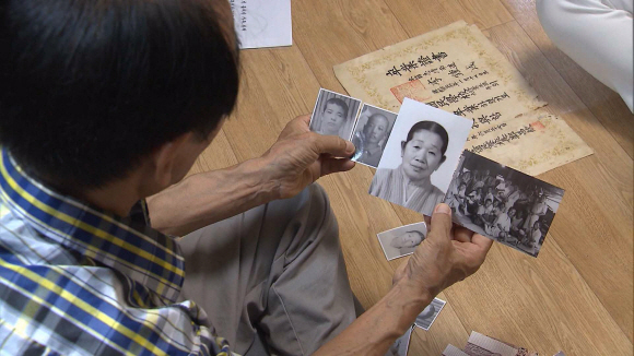 이산가족인 이수남씨가 15일 잃어버린 가족의 사진을 바라보며 회상에 젖고 있다. 공동취재단