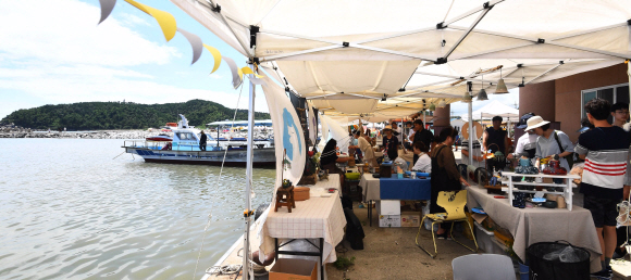 후진항 인근에서 열린 마켓을 찾은 여름 피서객들과 인근 지역 주민들이 다양한 문화 예술 체험장과 함께 판매 물품을 둘러보고 있다.