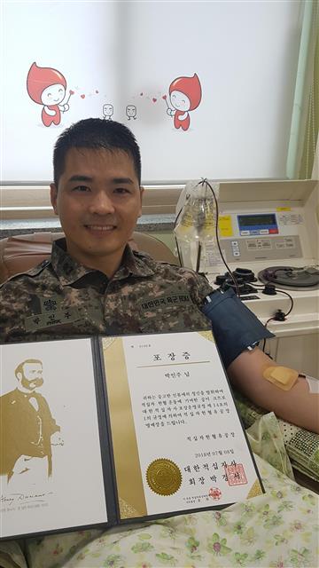 헌혈 100회를 달성해 받은 대한적십자사 유공 명예장을 들고 기뻐하는 박인주 소령.