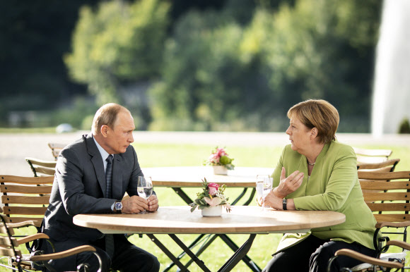 블라디미르 푸틴(왼쪽) 러시아 대통령과 앙겔라 메르켈 독일 총리가 18일(현지시간) 베를린 외곽 메제베르크궁에서 정상회담을 마친 뒤 공동 기자회견장으로 이동하기 전 야외 정원에 앉아 음료수를 마시며 담소를 나누고 있다.  베를린 EPA 연합뉴스