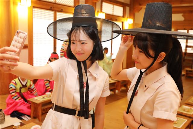 여름방학을 맞아 한국을 방문한 일본 고베(神戶) 쇼잉중학교·고등학교 학생들이 20일 대구 계명대학교 성서캠퍼스 한학촌에서 한복 체험 등 한국 전통문화를 체험하는 시간을 가졌다. 한복 체험을 준비하던 여학생들이 갓을 써보고 있다. 2018.8.20 뉴스1