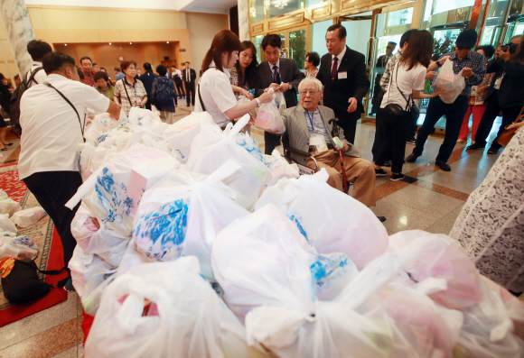 제21차 이산가족 상봉행사 1회차 둘째 날인 21일 오후 고성 금강산호텔에서 열린 단체상봉에 남측 가족들이 북측에서 준비한 다과를 건네받고 있다. 2018. 8. 21 사진공동취재단