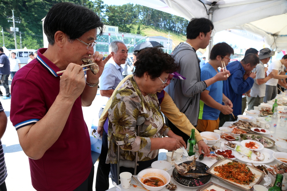  지난해 서천군 홍원항 전어·꽃게 축제장을 찾은 관광객들이 구운 전어를 두 손으로 잡고 맛있게 먹고 있다. 서천군 제공 