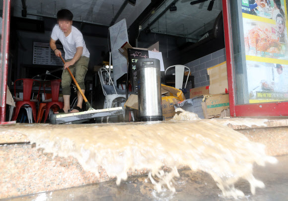 27일 오전 광주 남구 주월동의 한 식당이 한꺼번에 쏟아진 국지성 호우로 잠겨 업주가 물을 빼내고 있다. 2018.8.27  연합뉴스