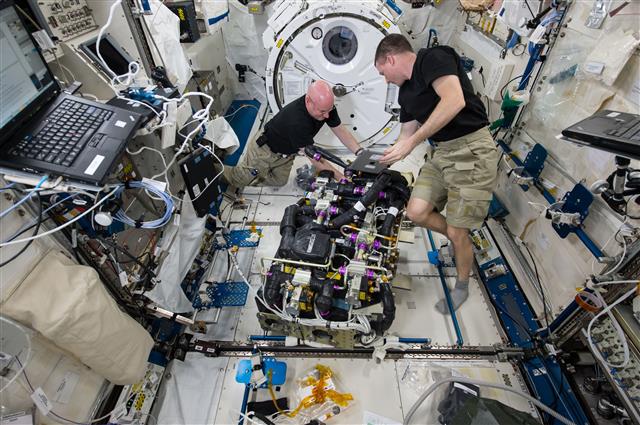 스콧 켈리(왼쪽)가 ISS에서 공기 정화기인 시드라를 동료 우주인과 함께 정비하고 있다.  클 제공