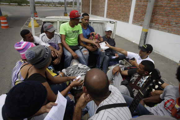 페루 국경도시인 툼베스에서 이민국 직원이 베네수엘라 난민들의 여권을 조사하고 있다. AP Photo/연합뉴스
