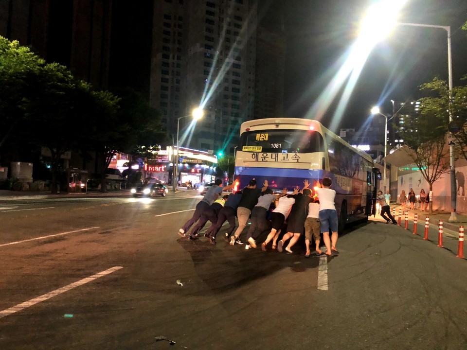 지난달 30일 오후 9시 20분경 부산 해운대구 시외버스터미널 앞 도로에서 유턴을 하다 고장난 시외버스 뒤에서 시민들과 경찰이 힘을모아 가장자리로 옮기고 있다. (부산지방경찰청 제공)