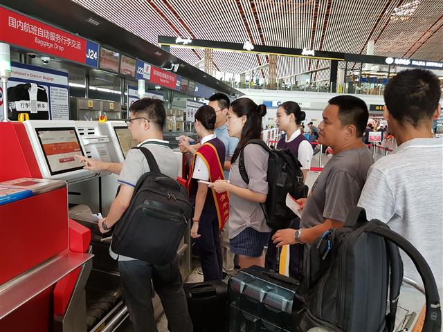 베이징 수도공항에서 승객들이 무인자동화 시스템을 이용해 탑승 수속을 밟고 있다. 항공사의 몇몇 직원들만 오가면서 승객들의 기기 조작을 돕고 있었다.