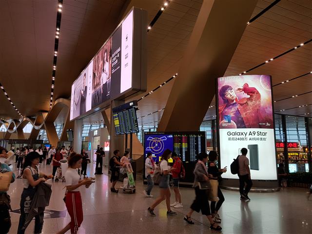 윈난성 쿤밍공항에 설치된 한국 핸드폰의 광고판 앞으로 승객들이 지나가고 있다