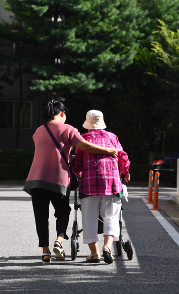 경기도 고양에 사는 임순달(57)씨가 지난 7일 치매에 걸려 거동이 불편한 시어머니를 모시고 산책을 하고 있다. 요양보호사인 임씨는 인근에 사는 치매 노부부에게도 방문요양서비스를 제공하는 등 홀로 세 명의 치매환자를 돌보고 있다. 안주영 기자 jya@seoul.co.kr