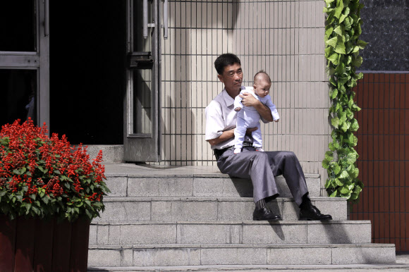북한의 한 남성이 11일(현지시간) 북한 평양의 거리에서 아기를 안고 있다. AP 연합뉴스