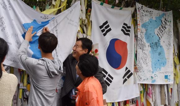 남북정상회담 선발대가 평양으로 출발한 16일 경기도 파주시 임진각에서 관광객들이 시설물에 설치한 한반도 깃발에 통일의 염원을 적어 넣고 있다. 2018.9.16. 이종원 선임기자 jongwon@seoul.co.kr
