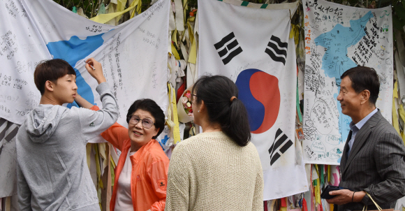 남북정상회담 선발대가 평양으로 출발한 16일 경기도 파주시 임진각에서 관광객들이 시설물에 설치한 한반도 깃발에 통일의 염원을 적어 넣고 있다. 2018.9.16.이종원 선임기자 jongwon@seoul.co.kr