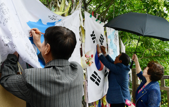 남북정상회담 선발대가 평양으로 출발한 16일 경기도 파주시 임진각에서 관광객들이 시설물에 설치한 한반도 깃발에 통일의 염원을 적어 넣고 있다. 2018.9.16. 이종원 선임기자 jongwon@seoul.co.kr