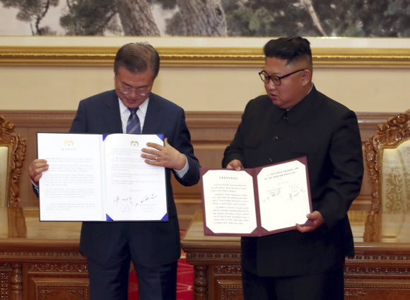 문재인 대통령과 김정은 국무위원장이 19일 백화원 영빈관에서 정상회담을 마친 뒤 평양공동선언서에 서명한 뒤 펼쳐 보이고 있다. AP 연합뉴스