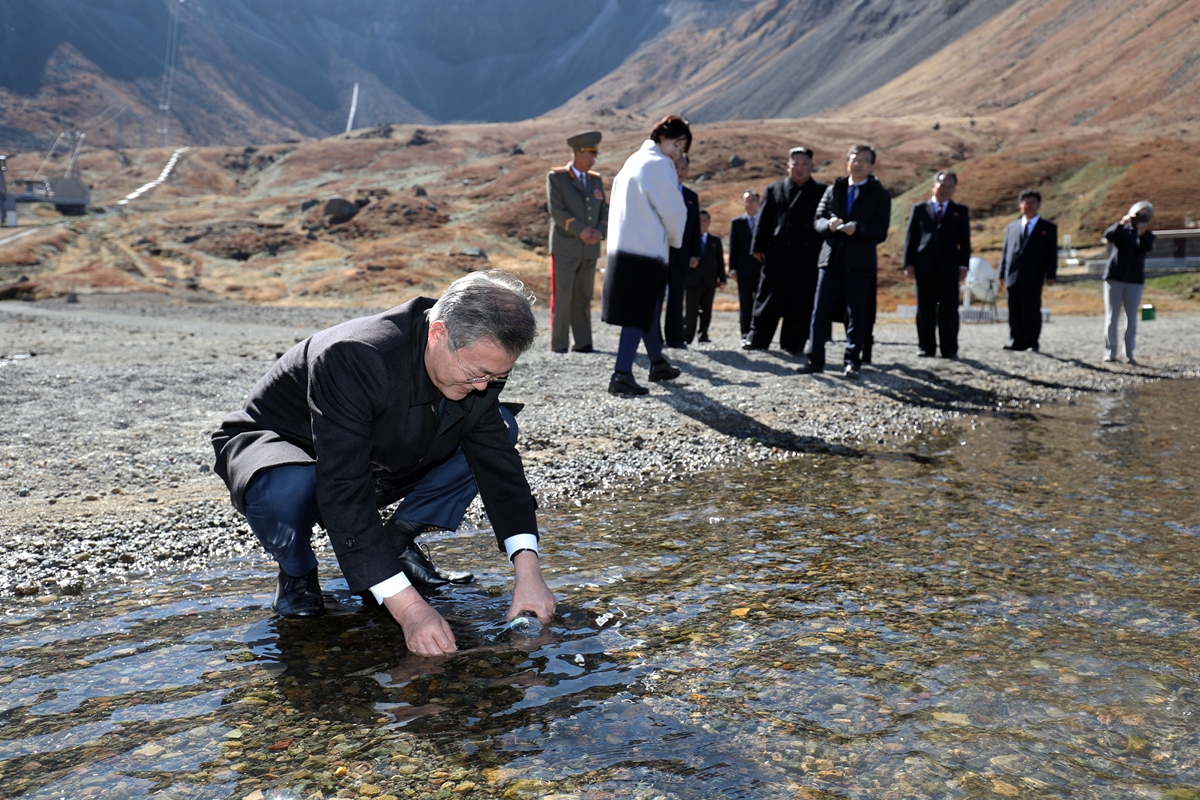 문재인 대통령이 백두산 천지 물을 생수병에 담고 있습니다. 이 모습을 강경화(오른쪽 첫 번째) 외교부 장관이 촬영하고 있네요. 평양사진공동취재단