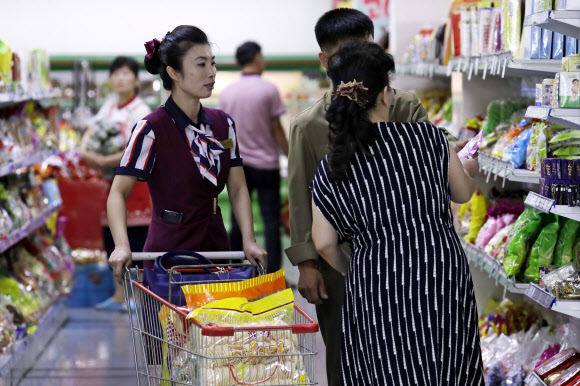 북한 주민들이 지난 12일 평양의 슈퍼마켓에서 직원의 도음을 받아 장을 보고 있다. AP 연합뉴스